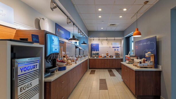 A modern kitchen area with a central island, a refrigerator with labeled compartments, and a counter displaying various food items. - Holiday Inn Express Jasper by IHG (Jasper)