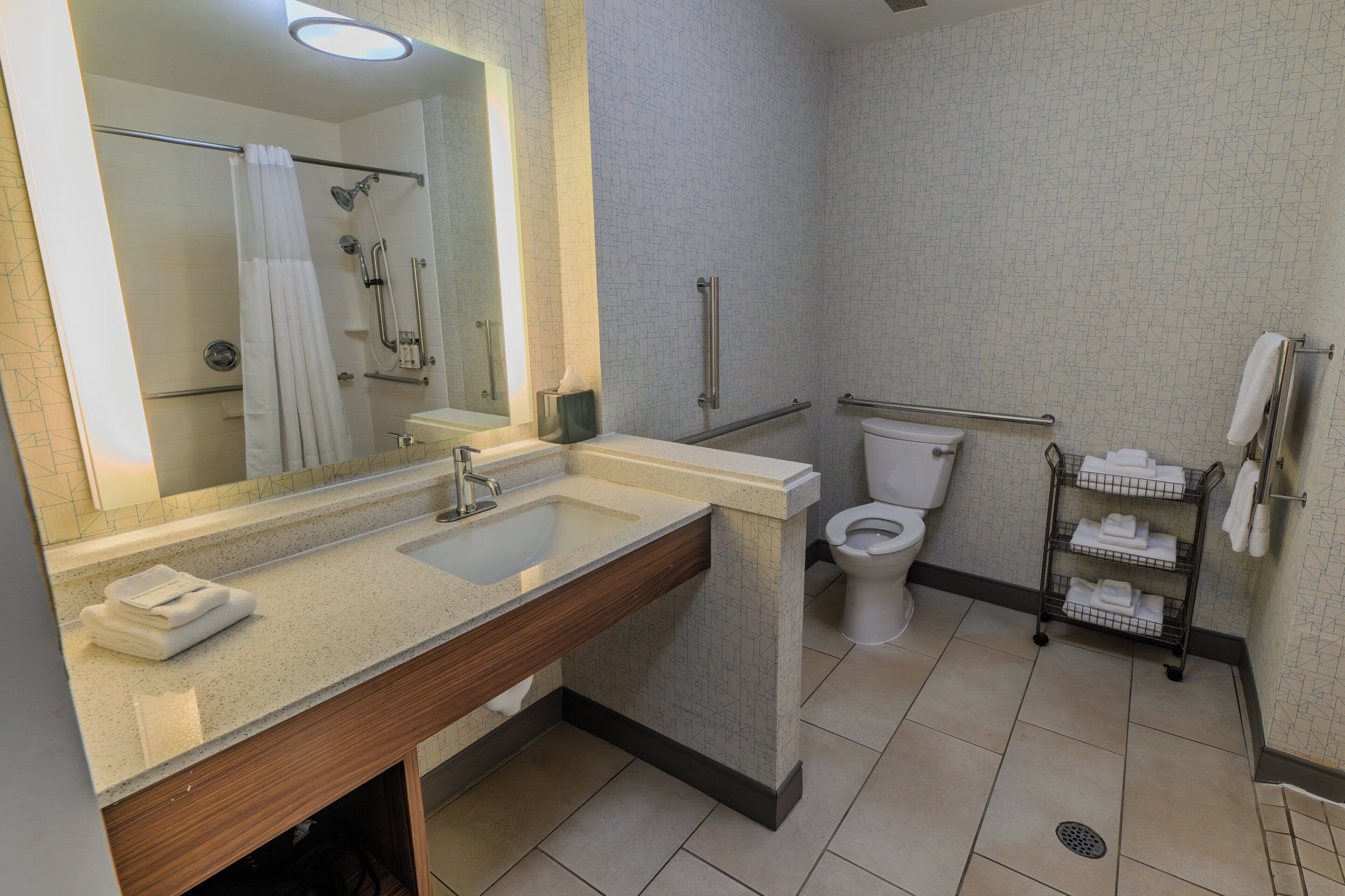 A modern bathroom with a sink, mirror, toilet, and shower.