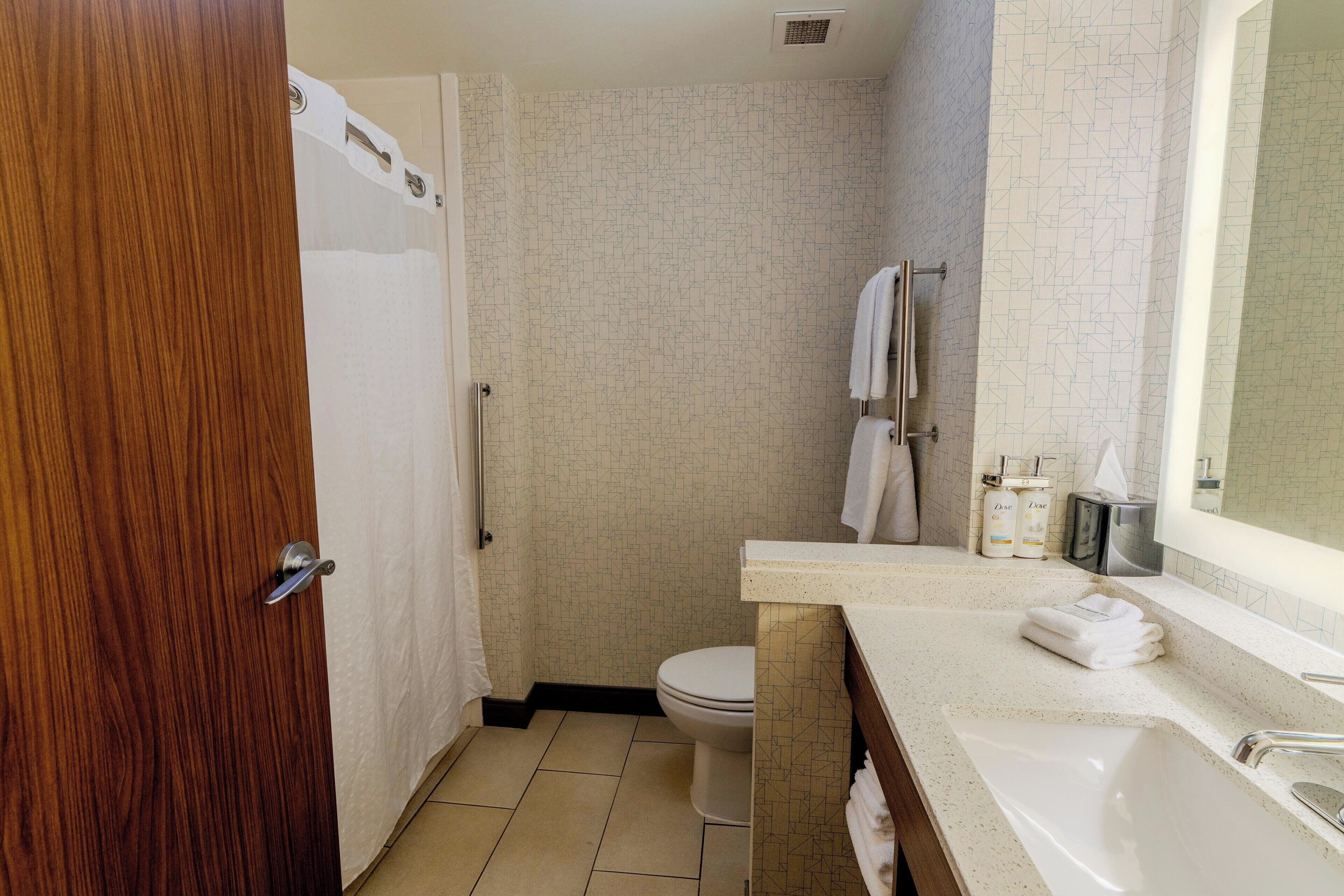 A bathroom with a shower, toilet, sink, and a towel rack.