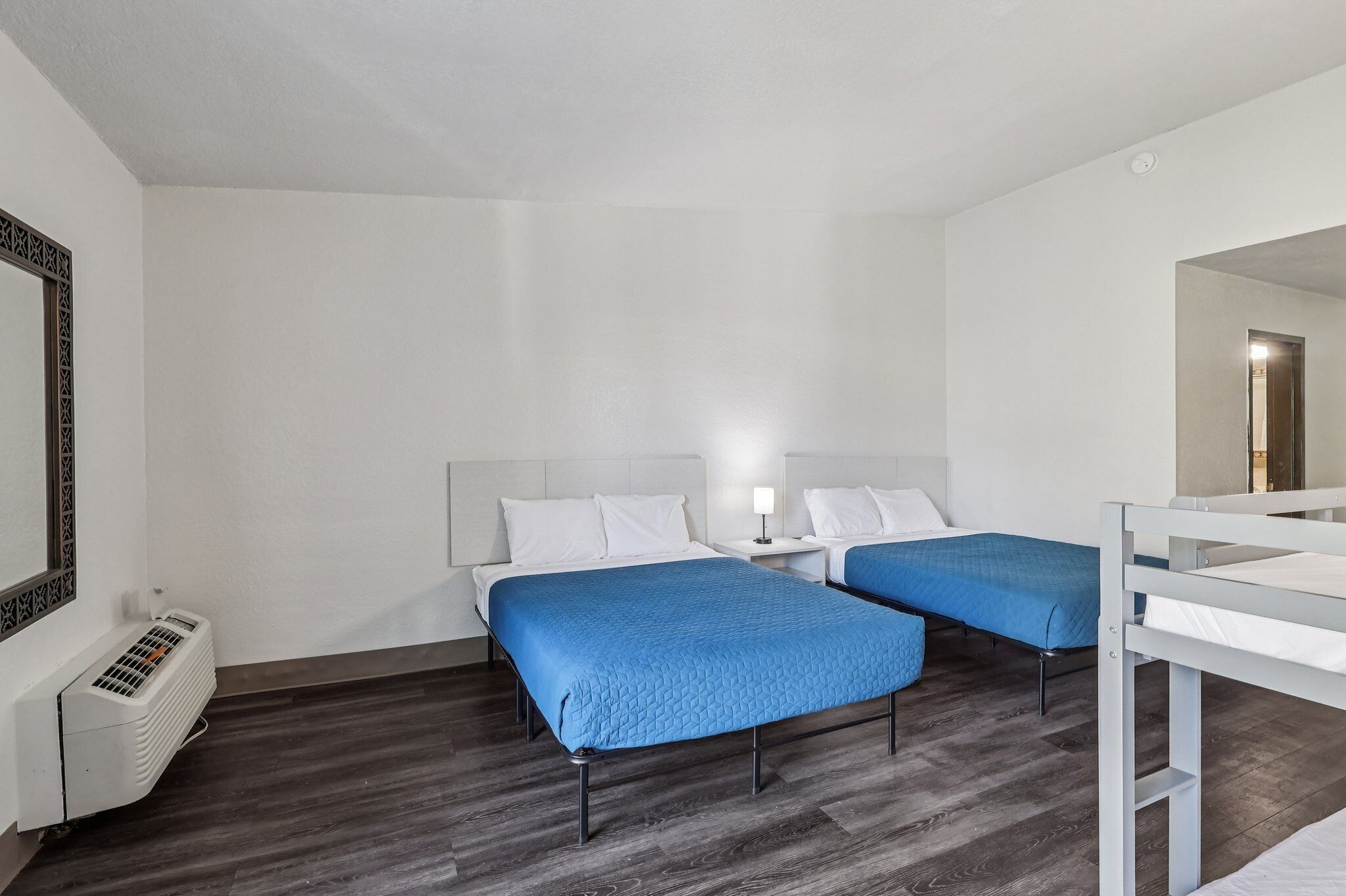 Habitación de hotel con dos camas, un radiador blanco y piso de madera.