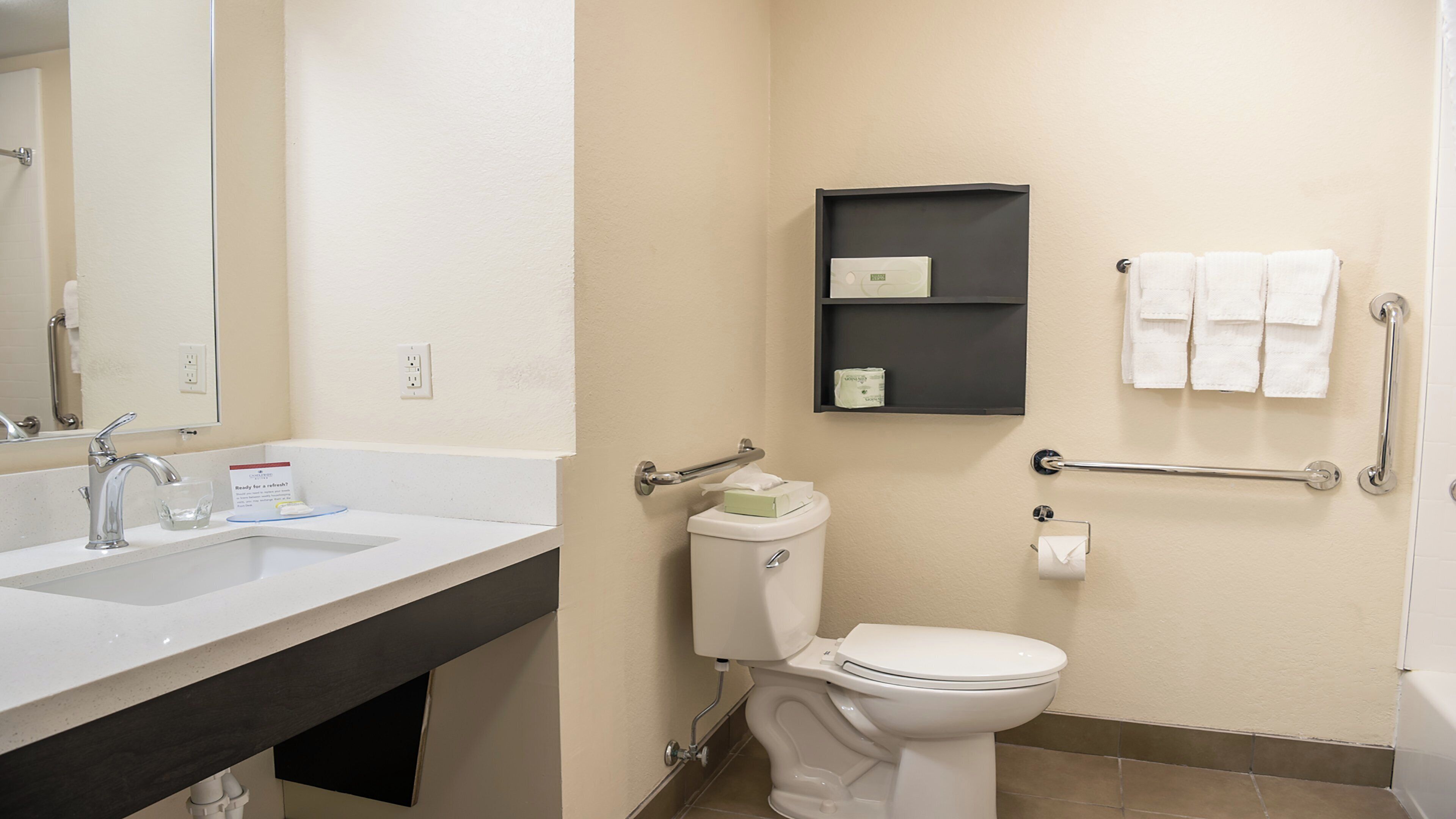 A bathroom with a sink, mirror, toilet, and towel rack.