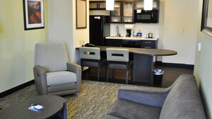 A compact living space with a kitchenette, two armchairs, a sofa, and a small coffee table. - Candlewood Suites Bay City by IHG (Bay City)