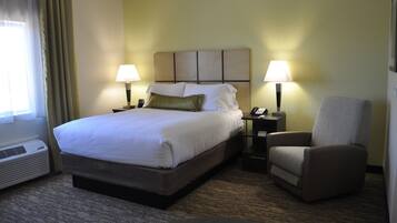 A hotel room with a large bed, two bedside tables with lamps, a chair, and a window with curtains.