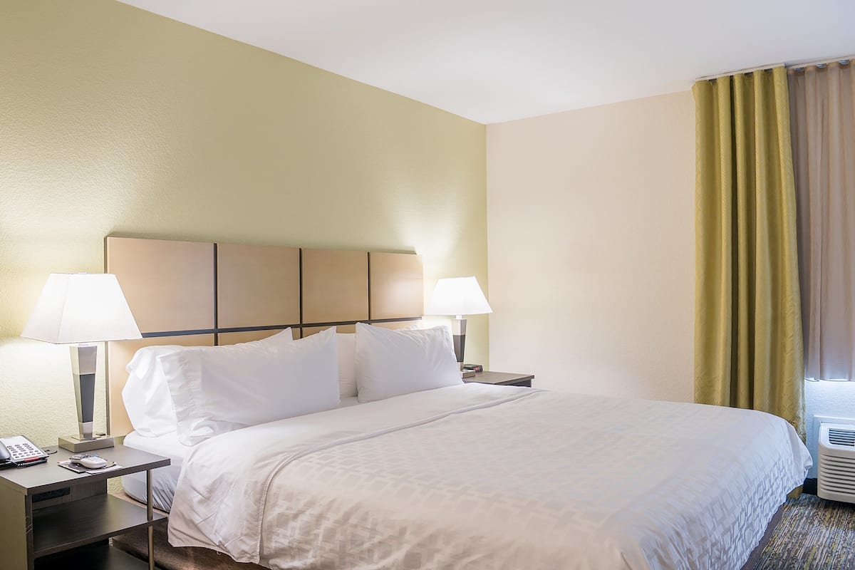 A hotel room with a bed, two bedside lamps, a telephone, and a nightstand.