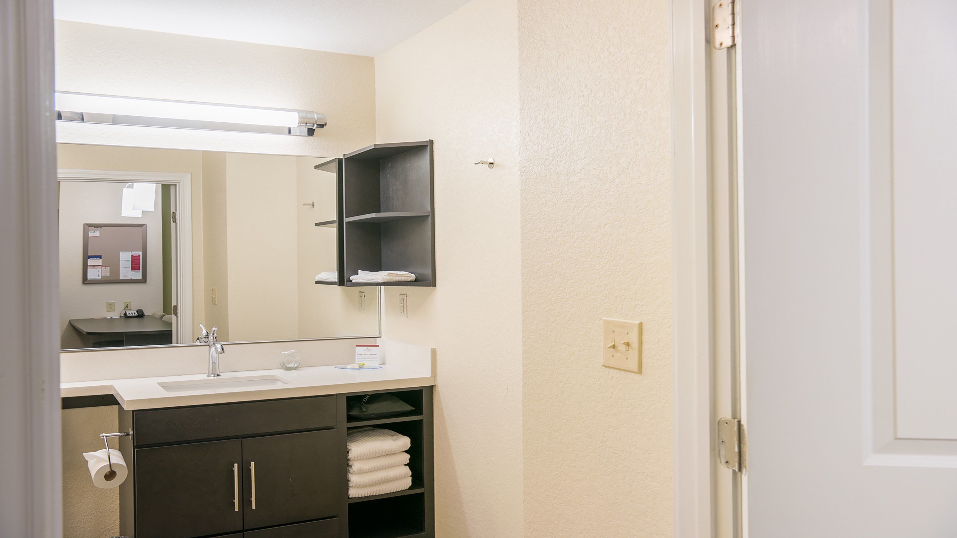 A bathroom with a sink, mirror, towel rack, and a door.