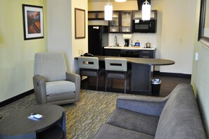 Un espacio habitable compacto con kitchenette, dos sillones, un sofá y una mesita de centro.