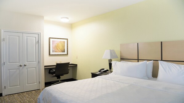 Habitación de hotel con cama, escritorio, silla, teléfono y un cuadro colgado en la pared.