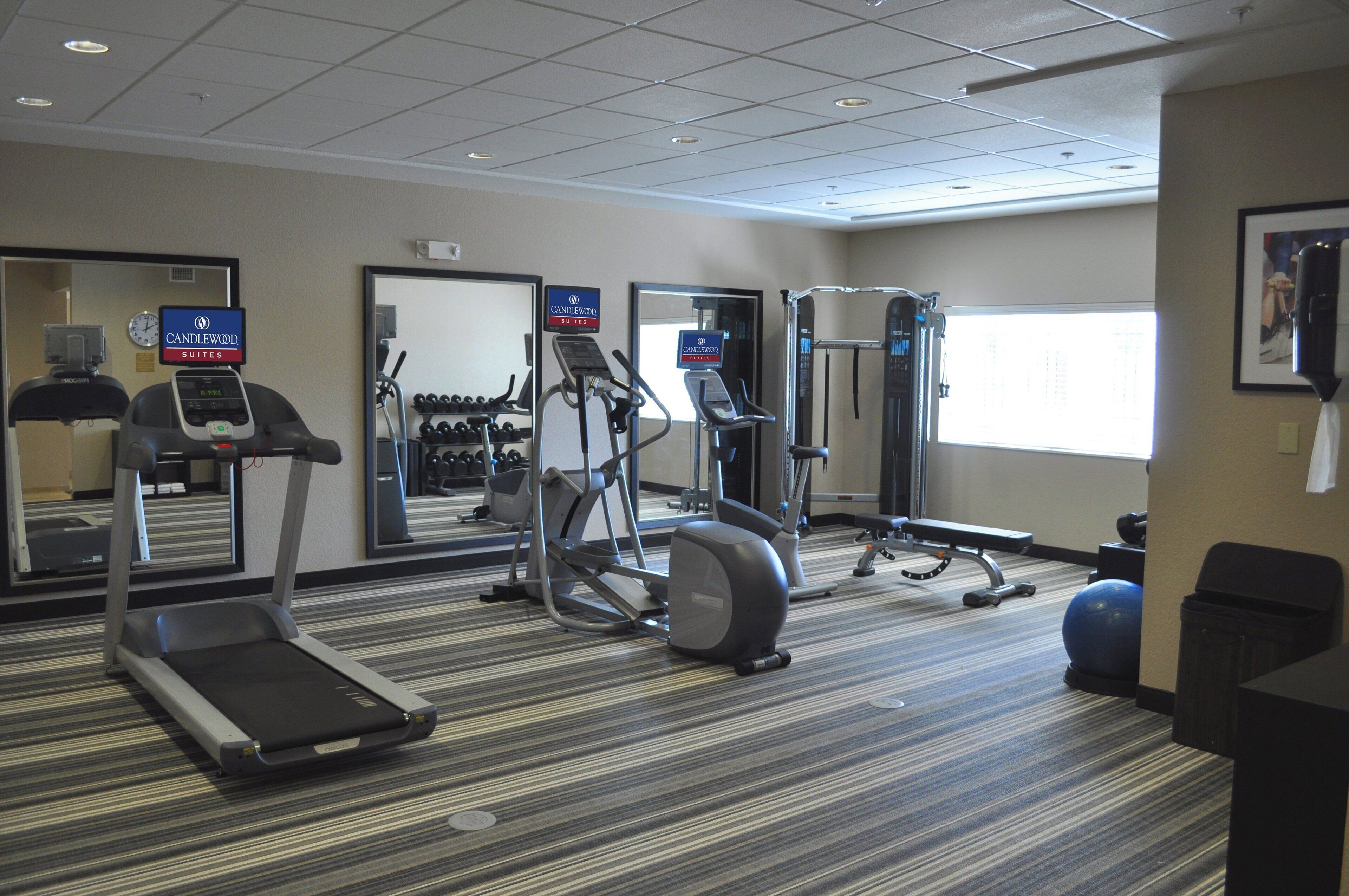 A hotel gym with treadmills, elliptical machines, and free weights.