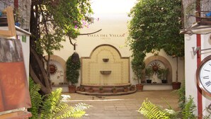 A courtyard with a fountain, potted plants, and a sign for Villa del Villar Hotel. - Hotel Villa del Villar (Querétaro)