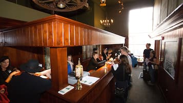 A bar area with wooden paneling, a chandelier, and a counter with a decorative lamp.