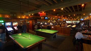 Zona de bar con mesas de billar, juegos de arcade y barra.