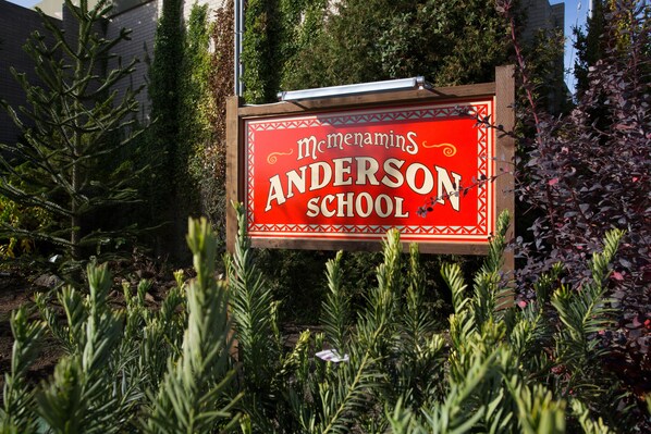 A sign for McMenamins Anderson School surrounded by greenery. - McMenamins Anderson School (Bothell)