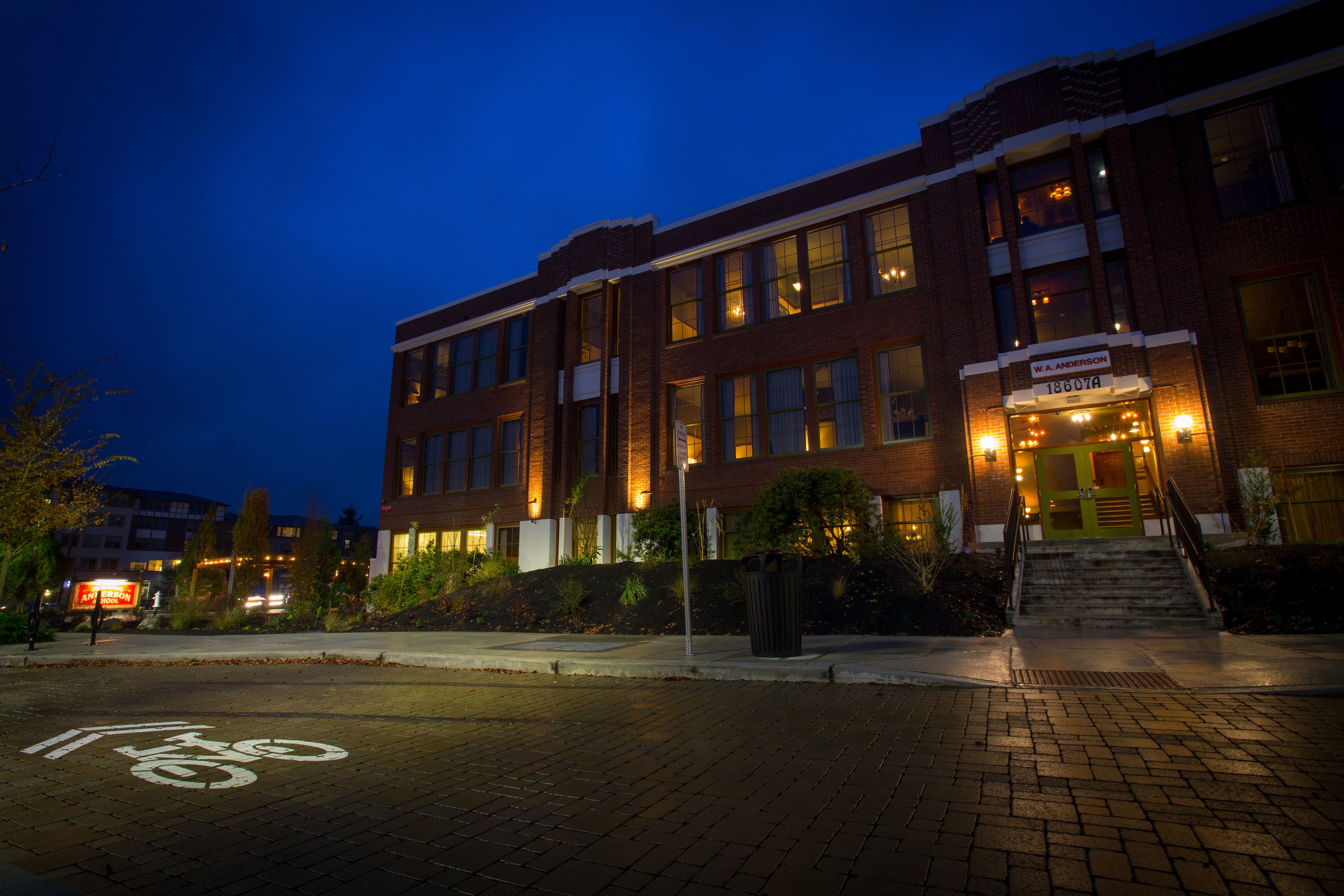 A brick building with a sign reading "W. Anderson" at the entrance, a bike lane on the pavement, and a staircase leading to the entrance.