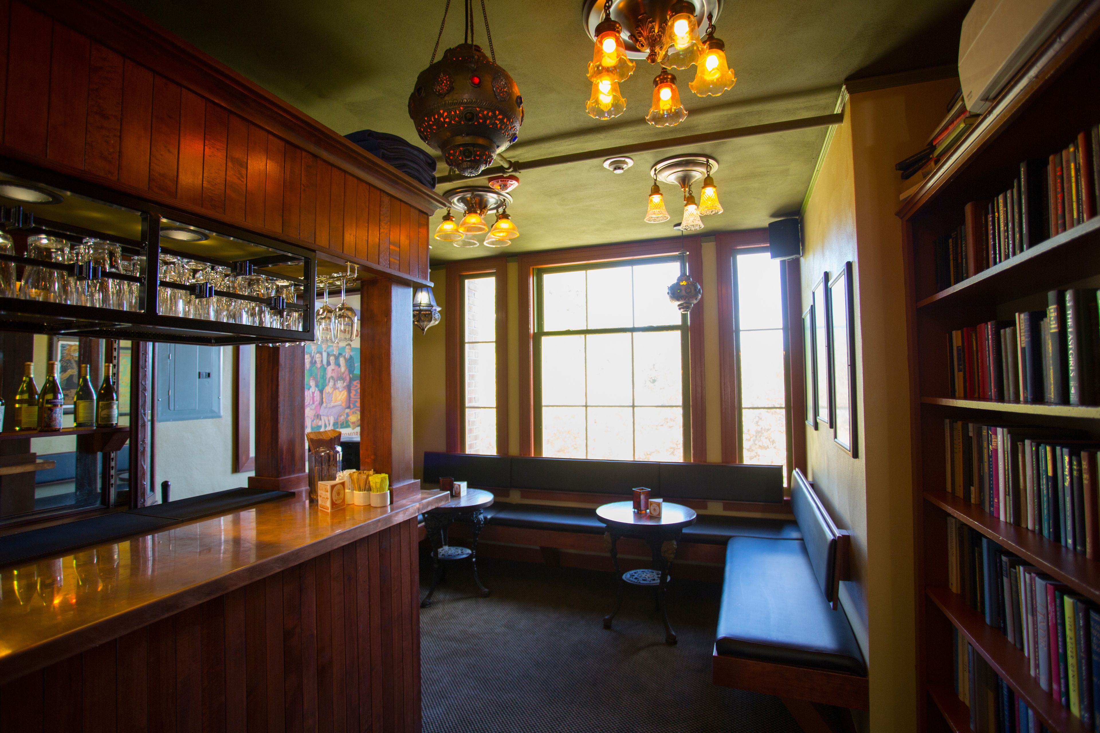 A bar area with wooden shelves, a bar counter, and a seating area with a bench and a small table.