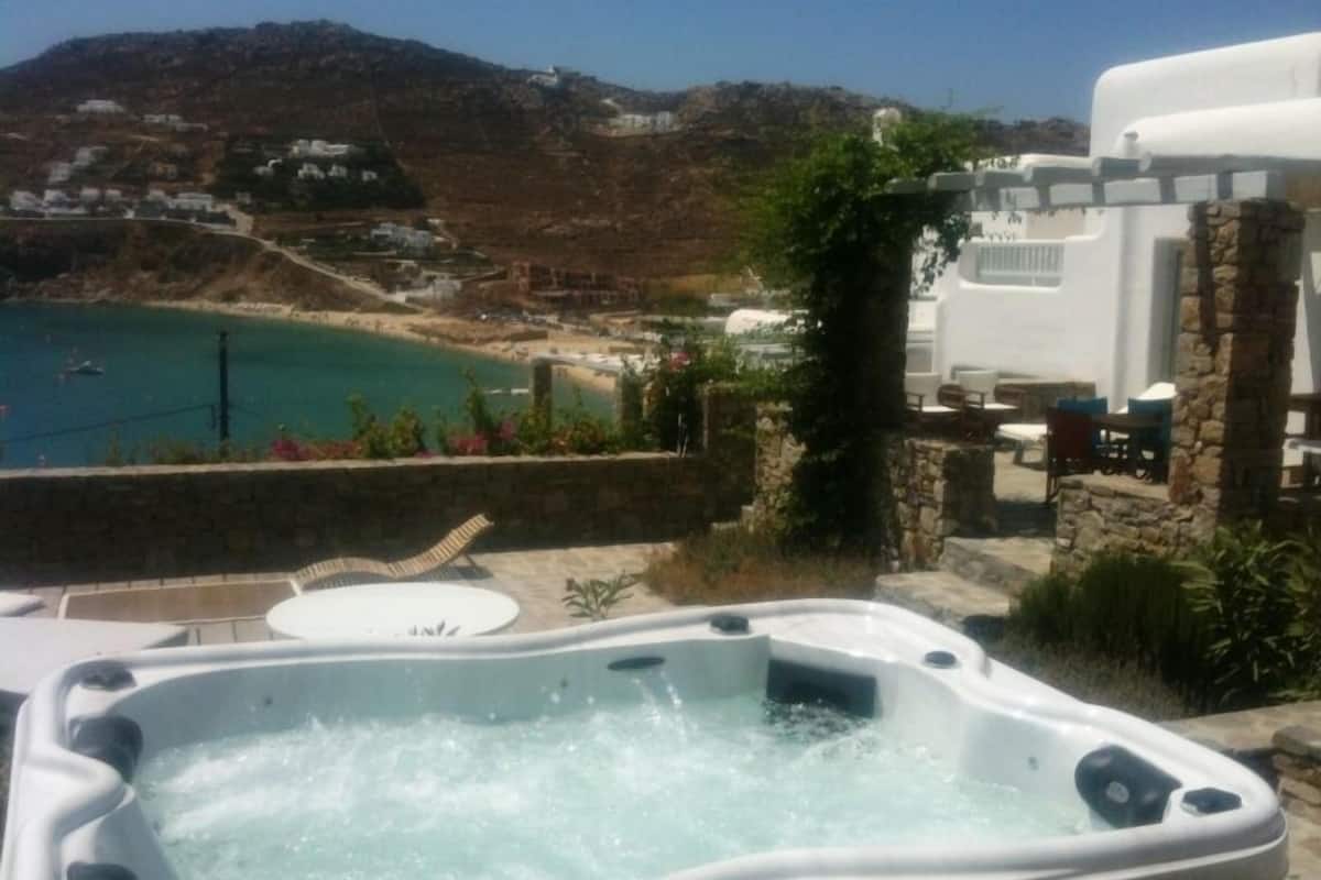 A hot tub with a view of a beach and hillside houses.