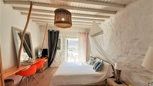 Un dormitorio con cama, escritorio, silla, lámpara y frutero.