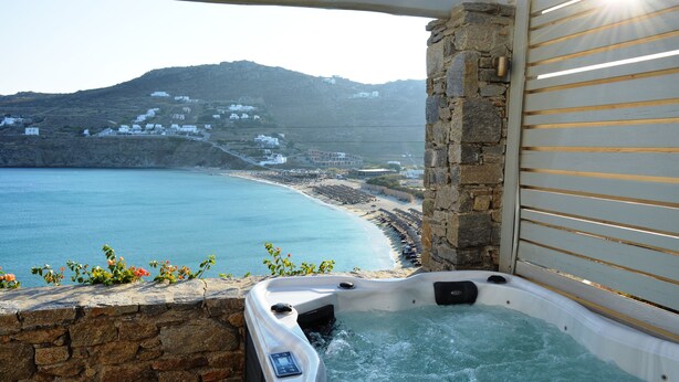 Un jacuzzi con vistas al litoral, paredes de piedra y barandilla de madera.