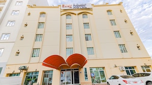 Un hotel con un vestíbulo amplio, múltiples ventanas y un cartel sobre la entrada.