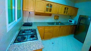 Una cocina con armarios de madera, estufa a gas, microondas y refrigerador.