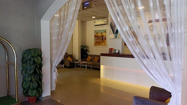 Un vestíbulo de hotel con una recepción, un área de descanso y una planta grande en maceta.