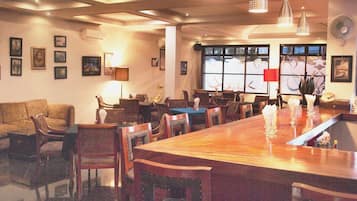 A restaurant with a long wooden table, multiple chairs, and pendant lighting.