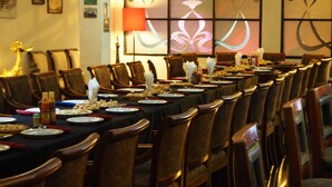 Un comedor con una mesa larga dispuesta para una comida, rodeada de sillas de madera.