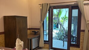 Quarto de hotel com cama, escrivaninha, guarda-roupa e vista para o exterior.