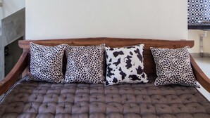 A room with a tufted sofa, patterned cushions, and a large abstract painting on the wall. - Villa D'Kerobokan (Denpasar)