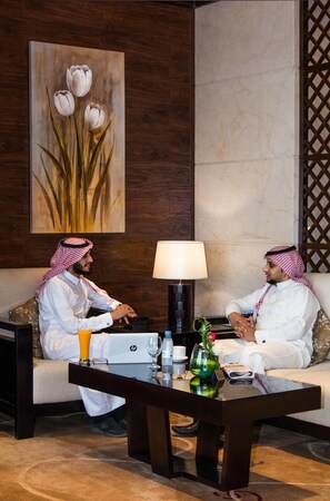 Two men seated on a sofa in a room with a wooden wall and a marble floor.