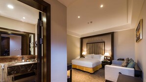 Ein Hotelzimmer mit Bett, Nachttisch, Lampe und einem Badezimmer mit Waschbecken und Spiegel.