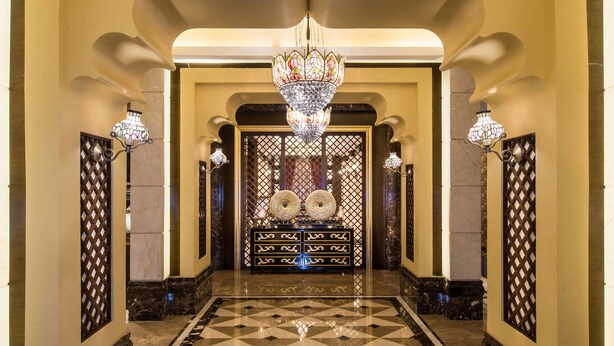 Eine prachtvolle Diele mit Schachbrettmuster, einem großen Chandelier und dekorativen Wandleuchtern.