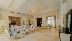 A spacious living room with a large sofa, armchairs, a coffee table, and a television. - Western Hotel - Madinat Zayed (Madinat Zayed)