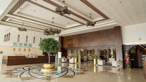 A spacious lobby with a reception desk, seating area, and a large decorative tree. - Western Hotel - Madinat Zayed (Madinat Zayed)