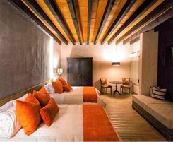 Een hotelkamer met twee bedden, een bureau, stoelen en een zithoek.
