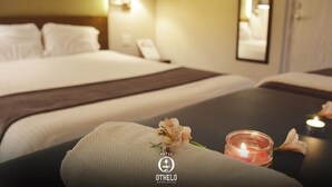 Una habitación de hotel con una cama, una mesita de noche con una vela y una toalla.
