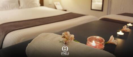 Une chambre d’hôtel avec un lit, une table de chevet avec une bougie et une serviette.