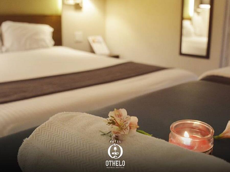 Una habitación de hotel con una cama, una mesita de noche con una vela y una toalla.
