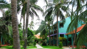 A tropical resort with a two-story building, palm trees, and a well-maintained lawn. - Hiep Hoa Resort (Mui Ne)
