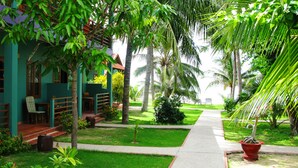 A tropical resort with a pathway leading to a building, surrounded by lush greenery and palm trees. - Hiep Hoa Resort (Mui Ne)