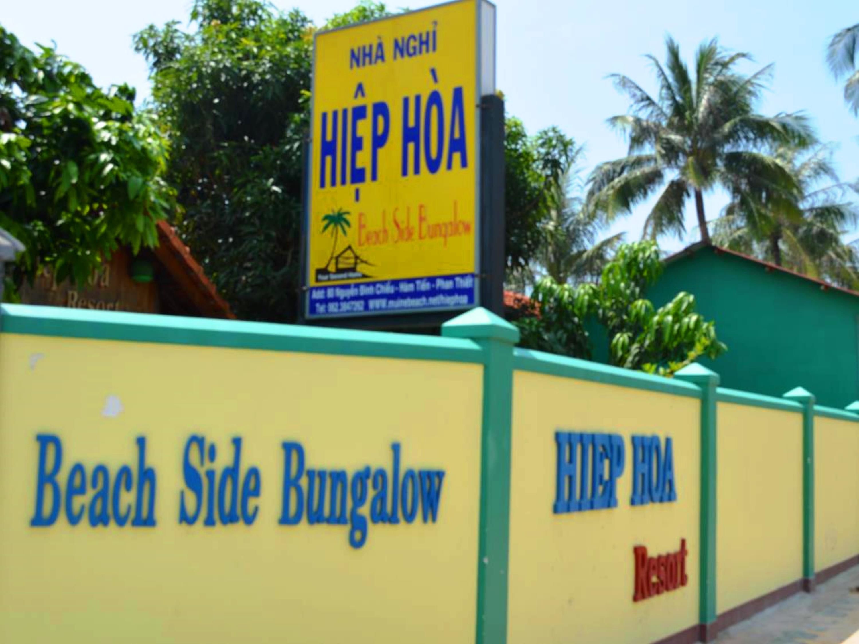 Un mur jaune sur lequel on peut lire les inscriptions « Beach Side Bungalow » et « Hiep Hoa Resort ».