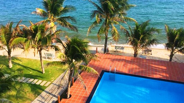 A pool area with a view of the ocean and palm trees. - Hiep Hoa Resort (Mui Ne)