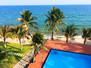 Zona de piscina con vistas al océano y palmeras.