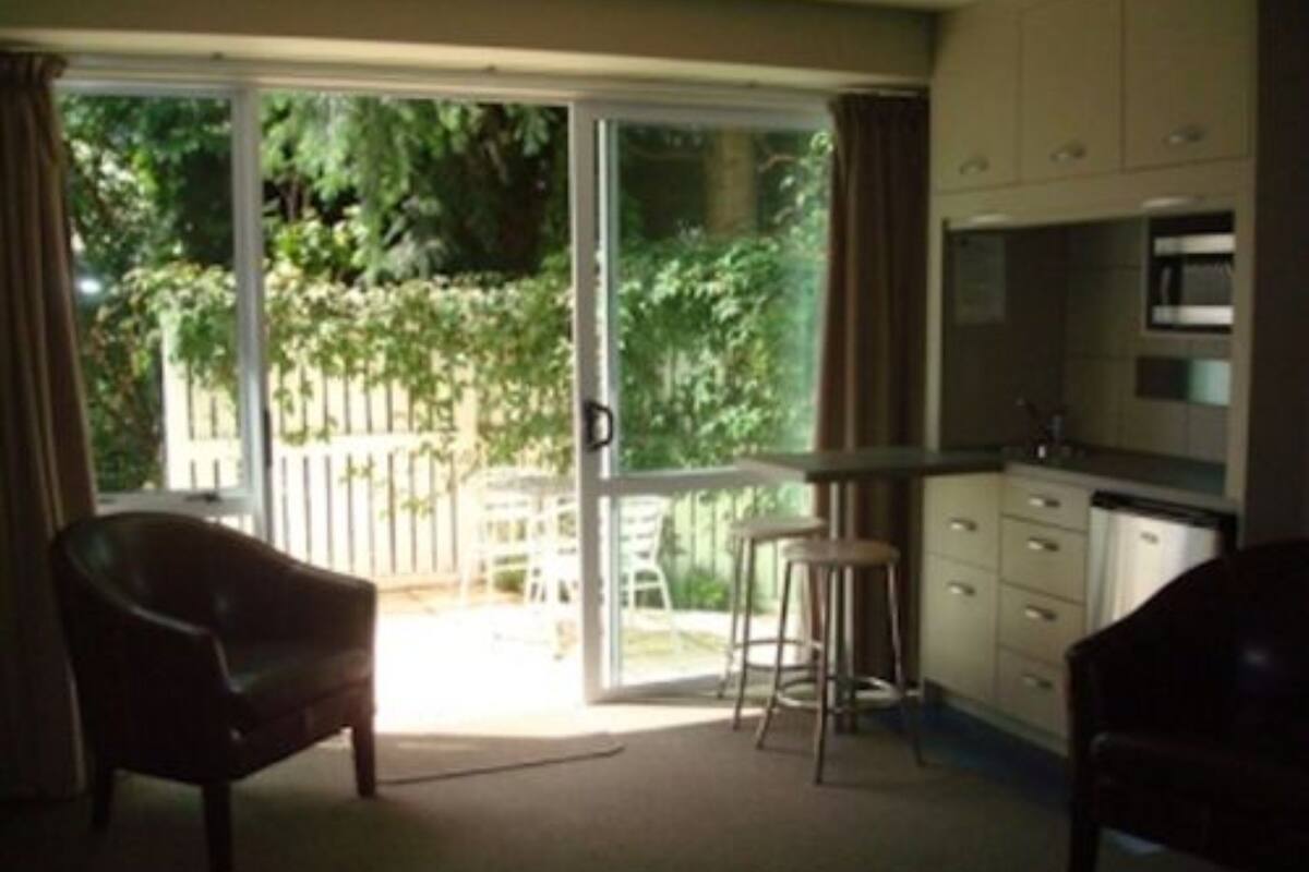 Une chambre dotée d’une porte-fenêtre coulissante donnant sur un jardin, d’une kitchenette équipée d’un four à micro-ondes et d’un coin repas avec une table et des chaises.
