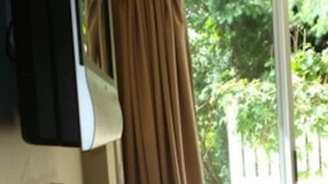 Une pièce dotée d’une grande fenêtre, d’un fauteuil en cuir marron et d’un téléviseur fixé au mur.
