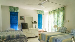 Un dormitorio con dos camas, un aparador, un televisor y una silla.
