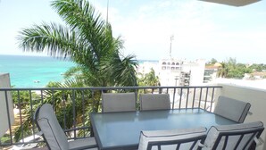 Ein Balkon mit Tisch und Stühlen mit Blick auf Strand und Meer.