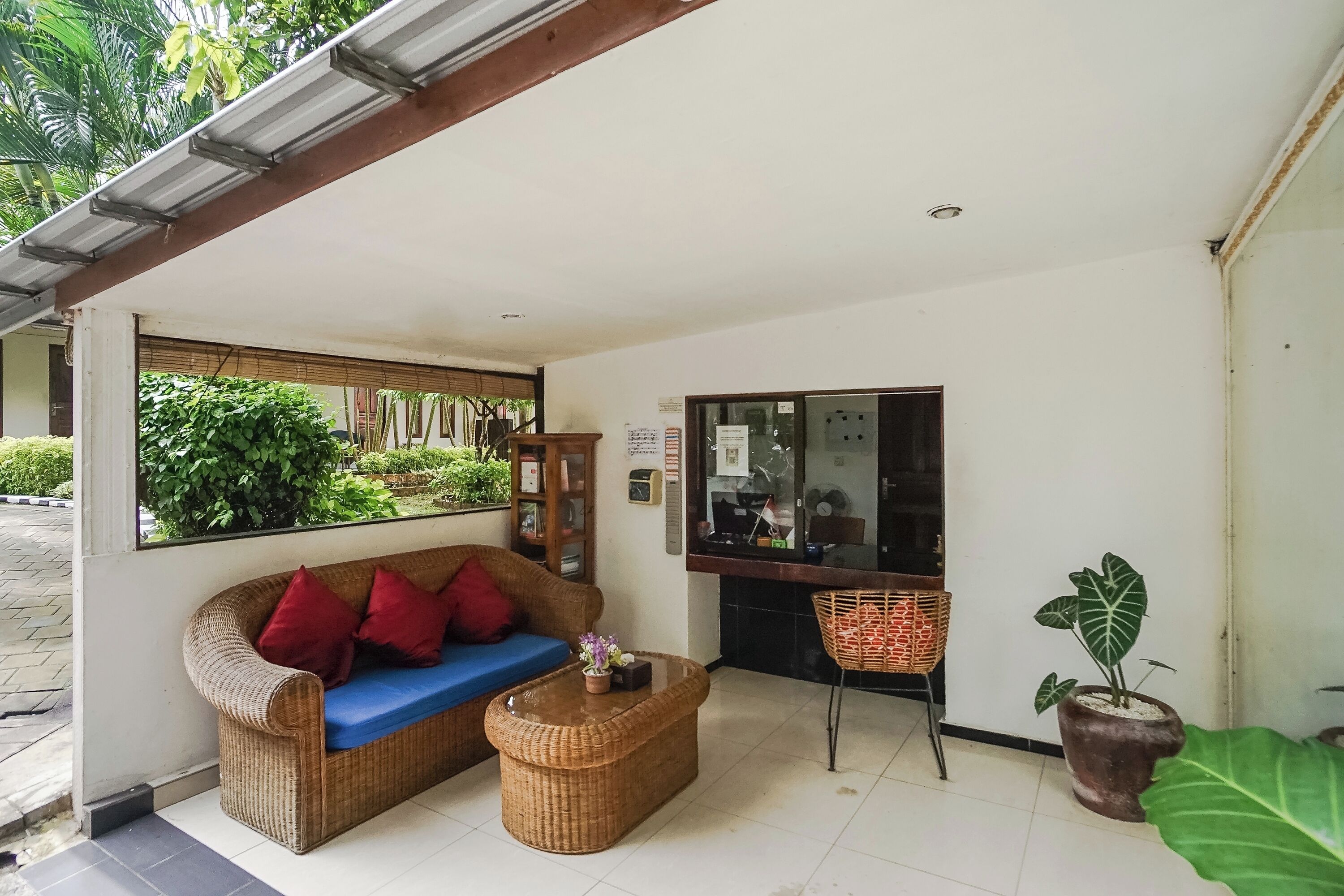 A room with a wicker sofa, a small coffee table, a television, and a potted plant.