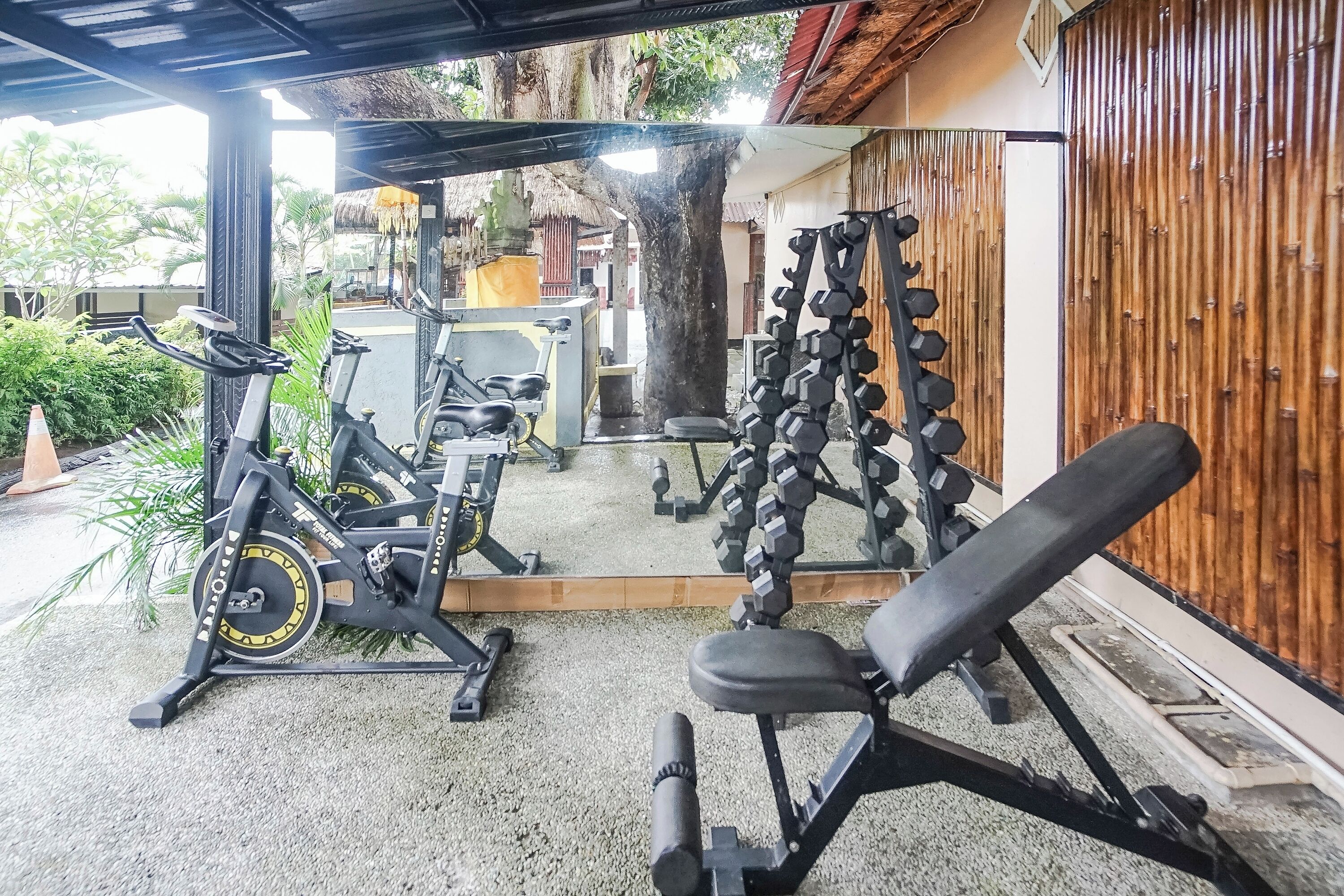 Une salle de sport équipée de matériel d’exercice, notamment un banc, des haltères et un tapis de course.