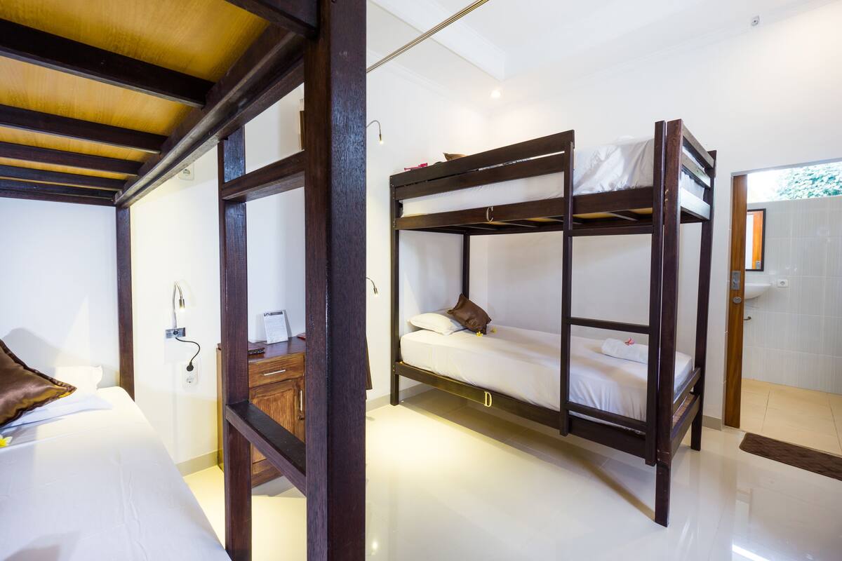 Una habitación con literas, un escritorio de madera y un baño con lavamanos.