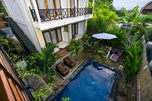 Uma área de piscina com uma piscina pequena, espreguiçadeiras e um espaço de estar coberto.